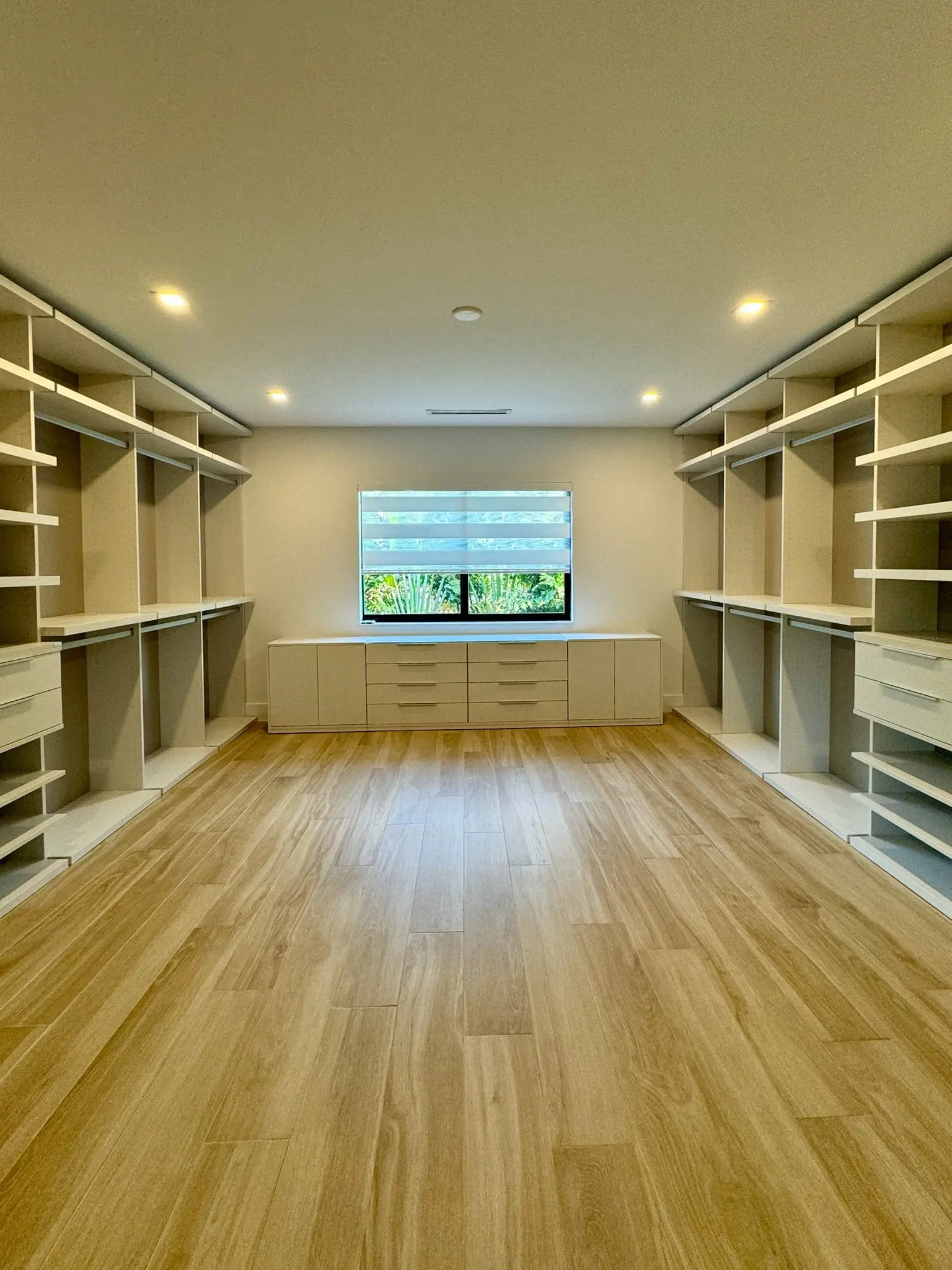 Custom built-in closet shelving and drawers with light oak flooring
