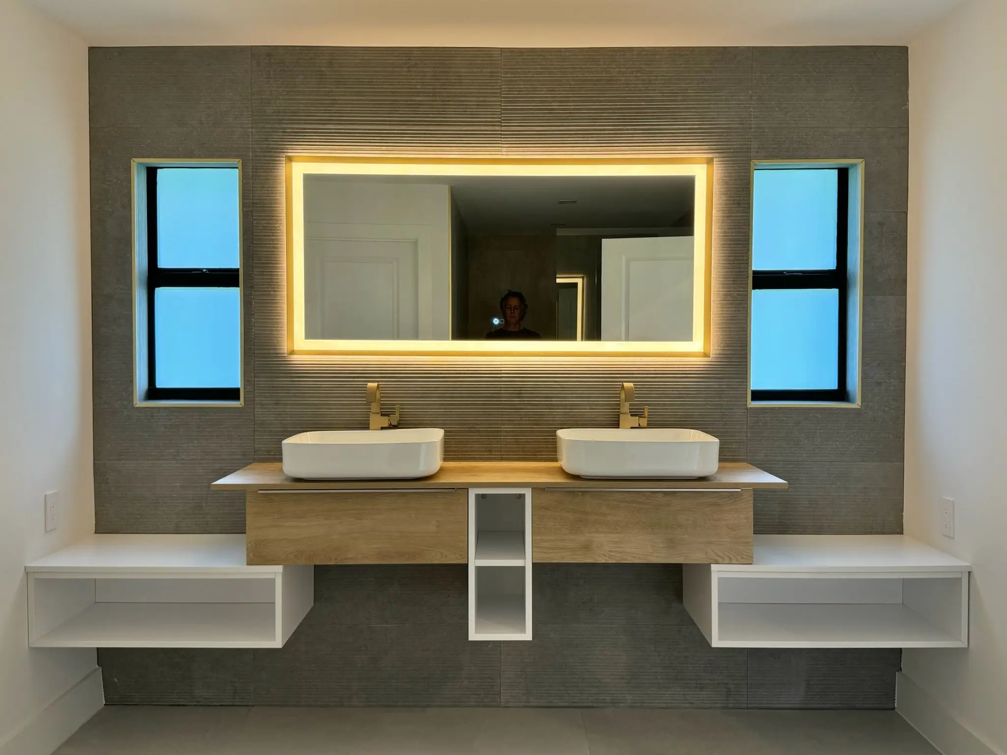 Bathroom renovation with a floating double vanity, vessel sinks, and a backlit mirror