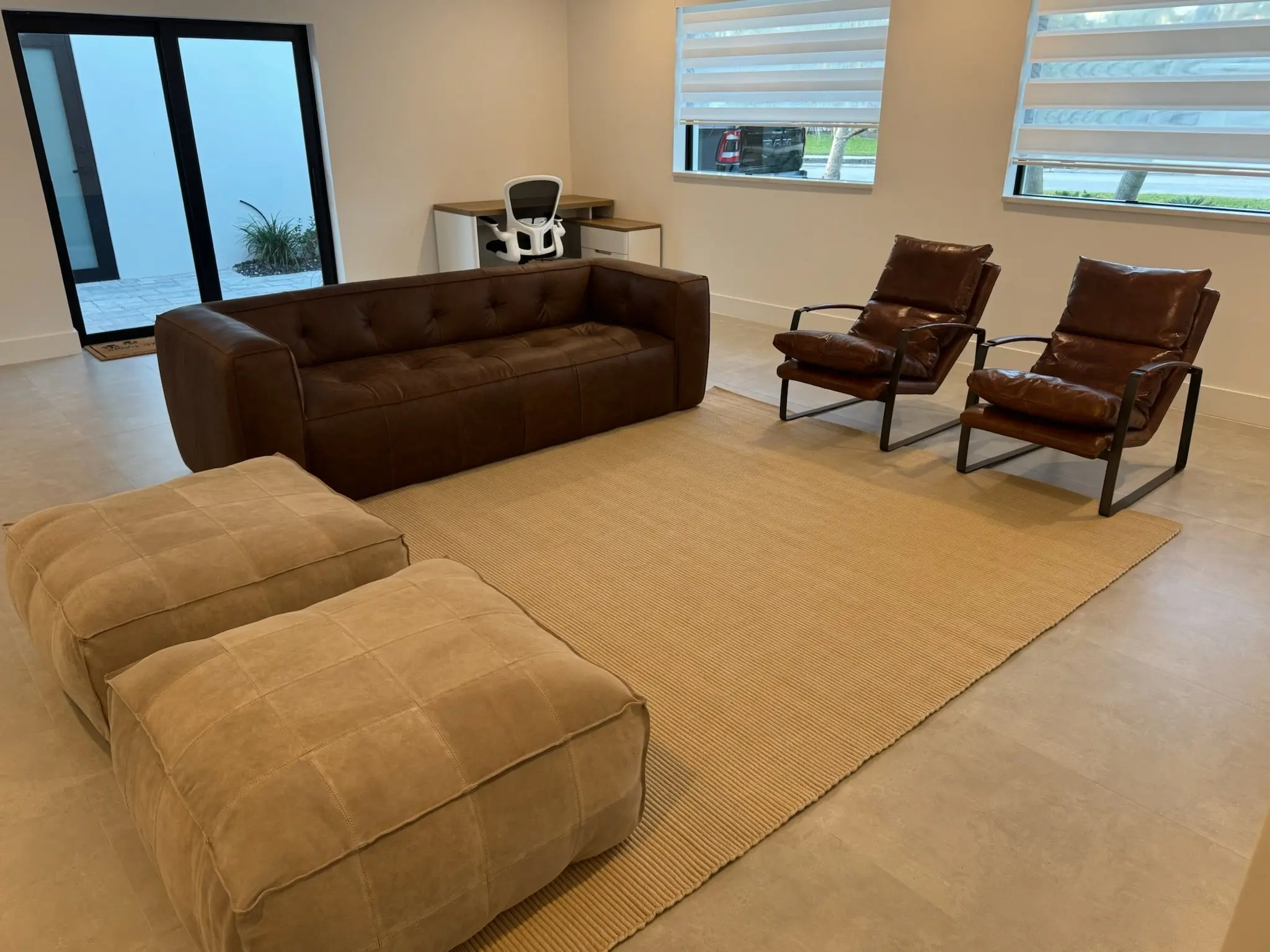 Open living room after a whole-home remodel, with large-format tile and black-framed windows