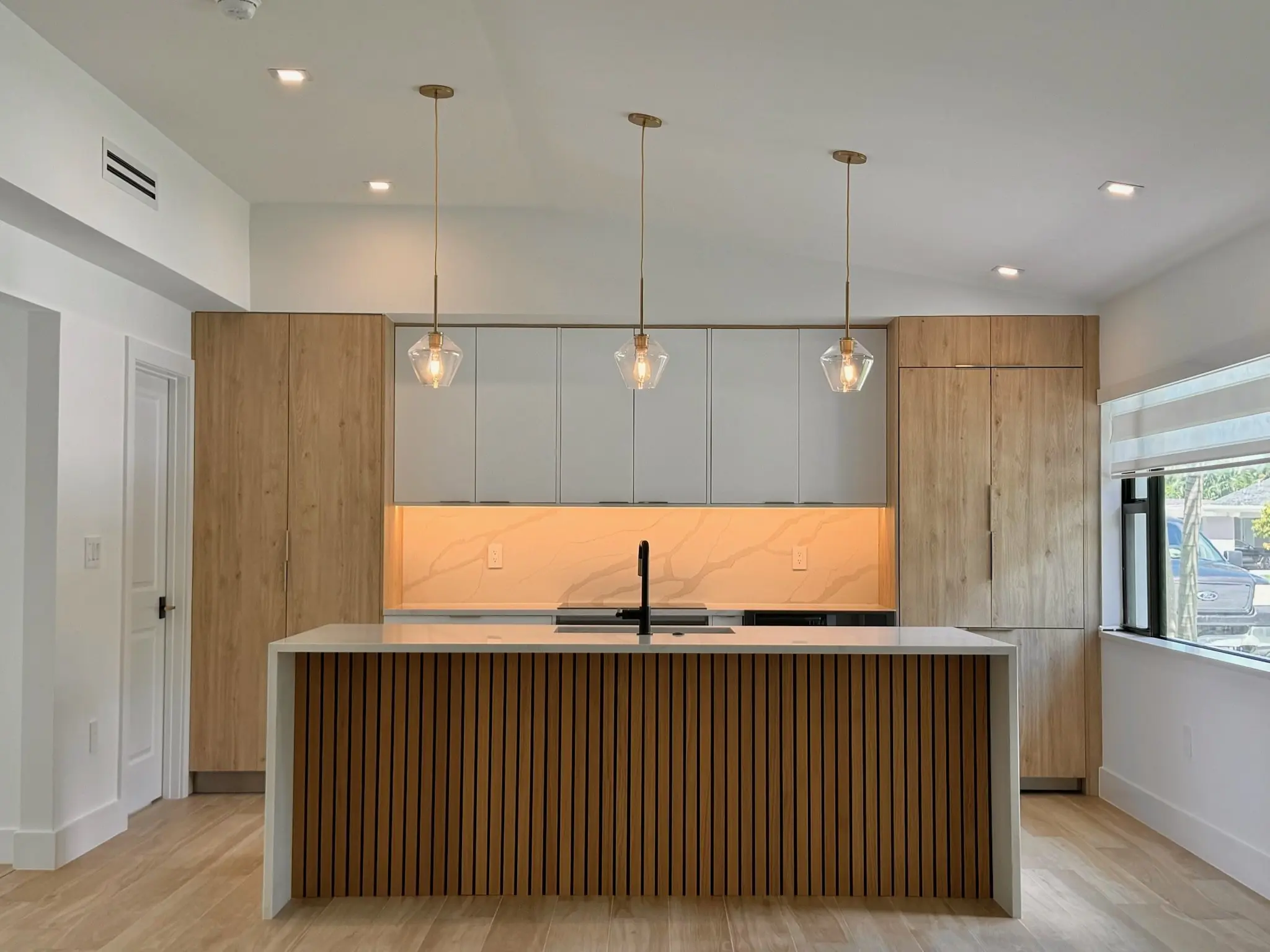 Modern kitchen remodel in Southwest Florida with a wood-slat island, quartz countertop, and pendant lighting